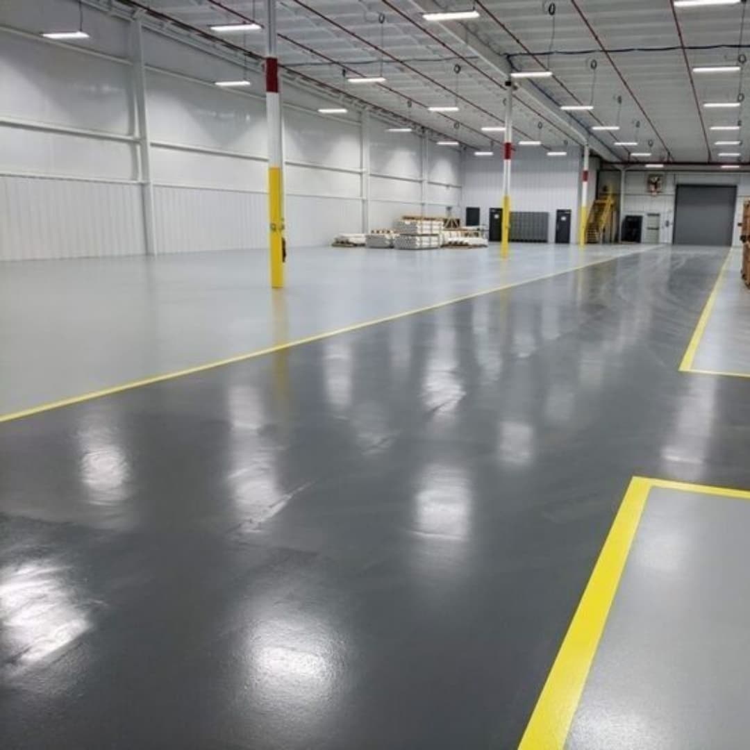 Grey epoxy flooring with yellow safety line markings in warehouse